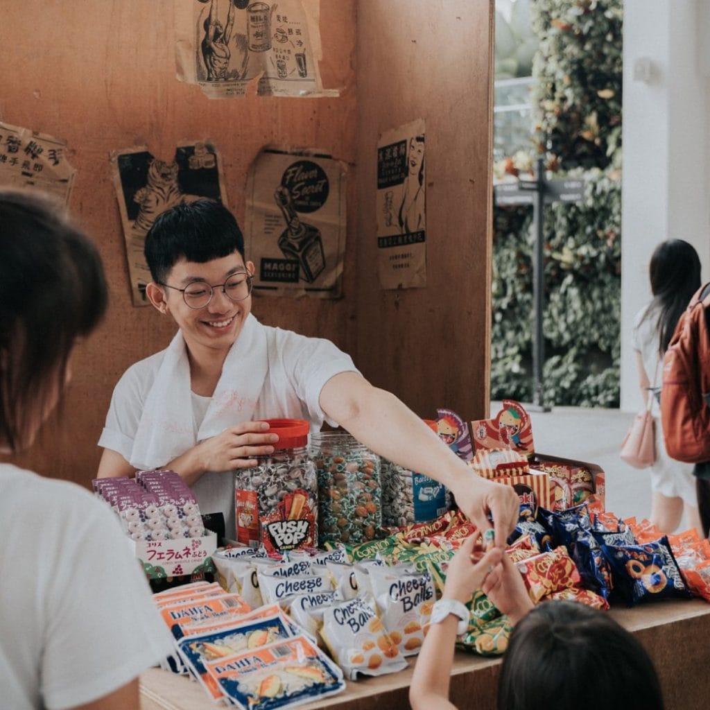 Man smiling while serving snacks from a retro-style stall