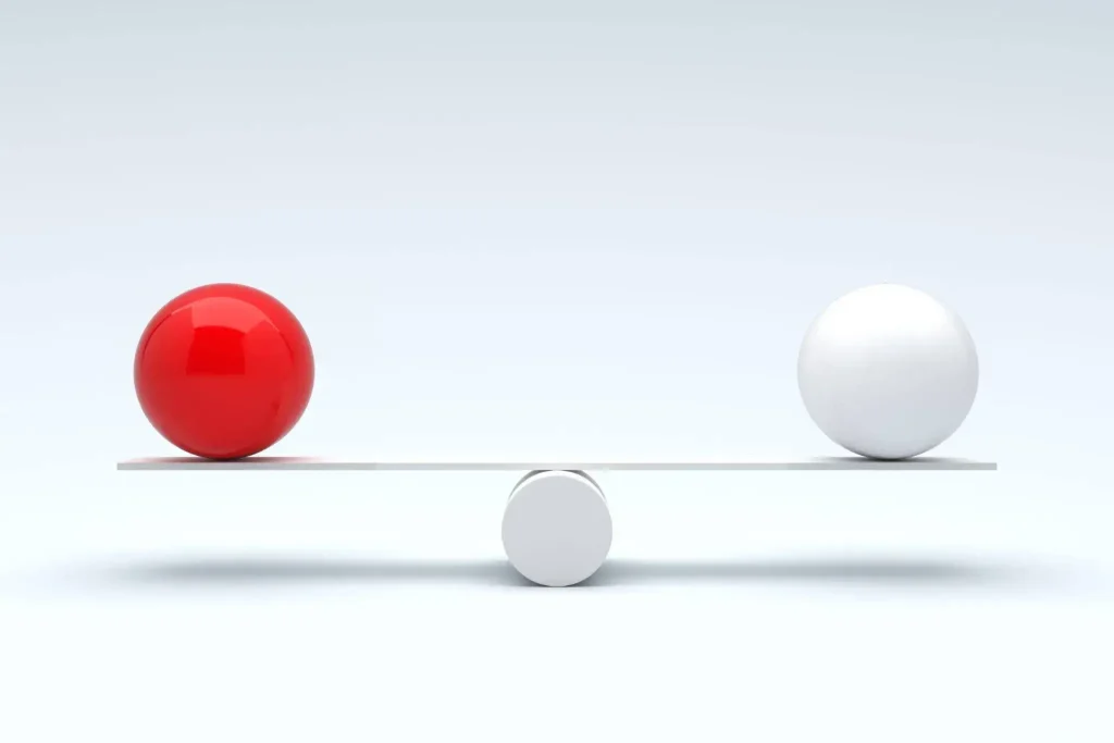 A 3D illustration of a red sphere and a white sphere balanced on opposite ends of a seesaw, symbolizing the comparison between in-house and outsourced company event management